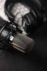 Microphone for podcasts and studio headphones on a PC keyboard on a black background, vertical frame