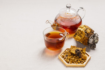 Wellness tea from chaga tree mushroom in a glass teapot and glass. Organic drink antioxidant gray natural background.