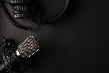 Studio black studio microphone with studio headphones on a black background. Banner. Radio, work with sound, podcasts. - 319095623