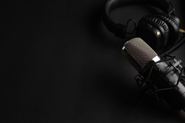 Studio black studio microphone with studio headphones on a black background. Banner. Radio, work...