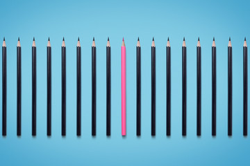 individual pink pencil among identical black pencils. Concept image