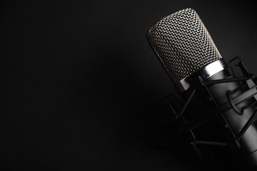 Black studio microphone on a black background with a pop filter with space for design, baner with space