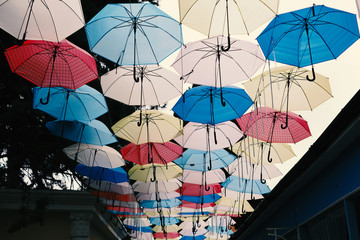 Fototapeta na wymiar Many multi-colored umbrellas on a background of the cloudy sky.