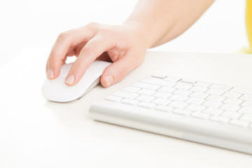 Woman typist using white keyboard and mouse to type and use computer