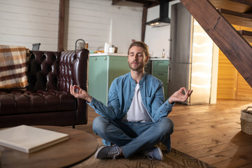 Concentrated young man practicing meditation at home