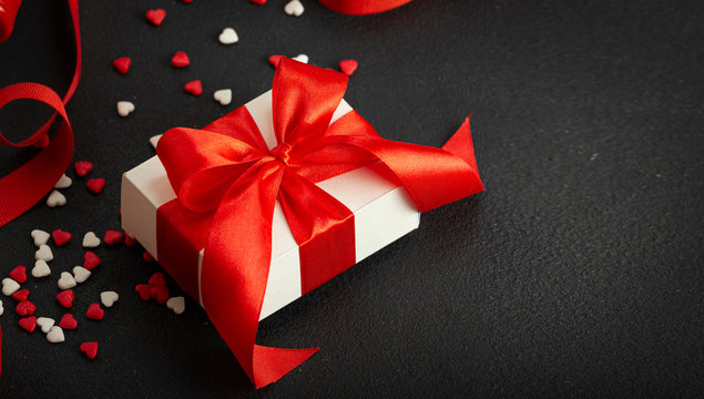 Valentine's Day, Mother's Day, March 8th. Gift box with a red bow and red ribbon, red hearts. Copy space.