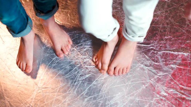 Close-up of the feet of children doing dance moves on a shiny floor.
