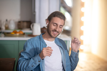 Naklejka premium Smiling man enjoying his favourite song in wireless earphones