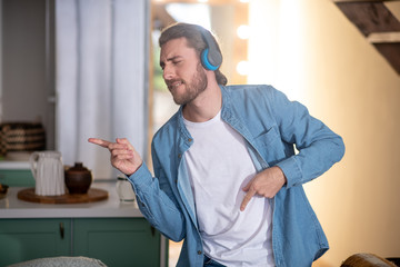 Emotional young man dancing while listening favourite music