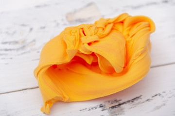 Orange mass for modeling on white wooden background.