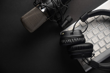 Flat lay, Studio microphone with professional headphones on a PC keyboard. Black on a black...