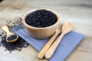 Riceberry cooked in a wooden cup Wooden spoons and wooden forks placed on fabric.