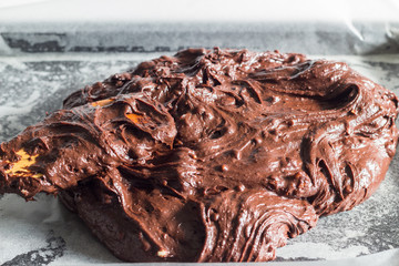 Chocolate brownie batter mix being filled in baking pan with wooden spoon