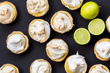 Lemon meringue tartlets made with lime isolated on black surface - overhead image close up © Madele
