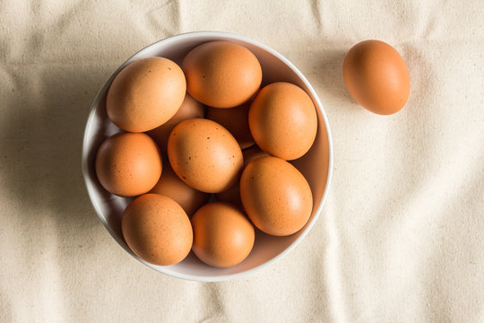 Chicken eggs in bowl on  rough cloth - top view brown farm chicken eggs image