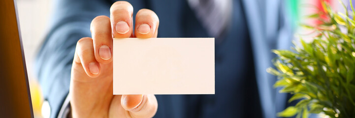 Male arm in suit give blank calling card to visitor closeup. White collar colleagues company name...