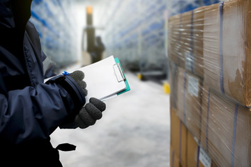 Closeup shooting hand of worker with clipboard checking goods in freezing room or warehouse