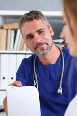 Male medicine doctor in blue uniform hold and give prescription to patient closeup. Panacea and life save prescribe treatment legal drug store contraception concept empty form ready to be used