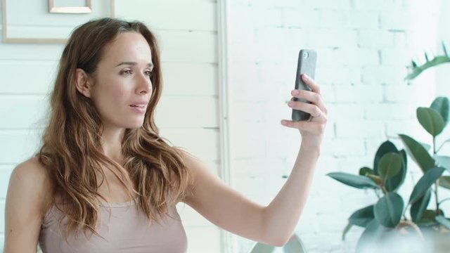 Macro beautiful pregnant woman taking selfie photo in bright bedroom.