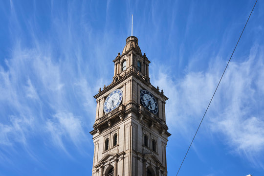 Historic Victorian style clock tower in Melbourne CBD with blue sky and white clouds