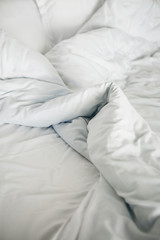 Crumpled white blanket on the bed after sleeping in the morning