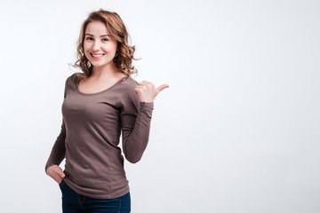Young smiling girl shows finger sideways. White background, closeup.