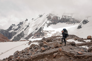 Naklejka premium Man standing on the rocks around the snow remnants in the mountains
