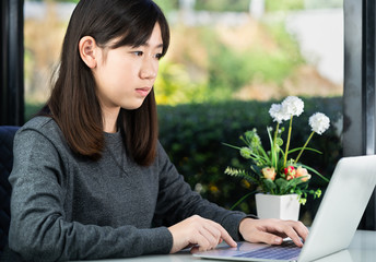 Teenage student using laptop doing homework at home