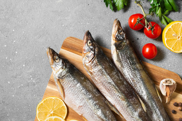 Smoked or dried smelt fish on a wooden Board on a gray kitchen table. Top view with space for text	