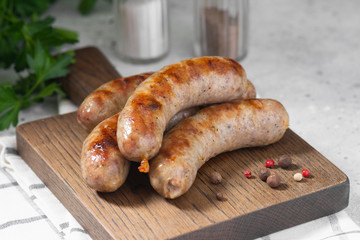 Grilled sausages on a wooden Board on a light gray kitchen table