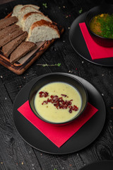 Set of different soups. Chicken broth, red borsch, lentil with bacon, mushroom cream soup. Delicious fragrant first courses. Festive table with delicious food on black boards.