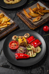 Grilled vegetables appetizer: zucchini, mushrooms, corn. Octoberfest party dinner. Festive table with delicious food on black boards.