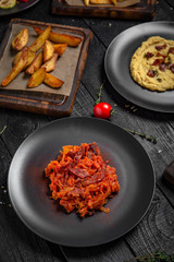 Appetizers from grilled vegetables, potatoes, crushed beans or hummus, stewed cabbage. Octoberfest party dinner. Festive table with delicious food on black boards.