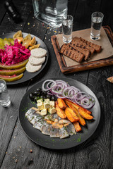 Snack for vodka. Salted herring with onions, potatoes and pickles: watermelon, tomatoes, cucumbers. Festive table with delicious food on black boards.