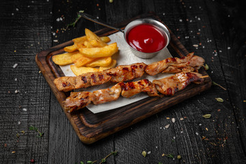 Grilled chicken pieces on skewers with sauce. Octoberfest party dinner. Festive table with delicious food on black boards.