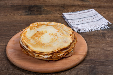 A stack of pancakes lies on a round board. Close-up, angle view, Flat Lay, Copy space, place for text. Shrovetide, East Slavic traditional holiday of Ukraine.