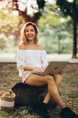 Young attractive woman using Laptop while sitting in garden during weekend, working an urgent case assignment from company. Business model can work online everywhere, every time by using network.