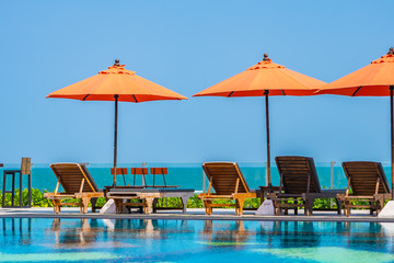 Fototapeta na wymiar Umbrella and chair around outdoor swimming pool neary sea in hotel resort