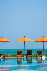 Umbrella and chair around outdoor swimming pool neary sea in hotel resort