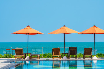 Umbrella and chair around outdoor swimming pool neary sea in hotel resort