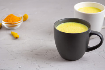 Two cups with Golden milk on a gray background
