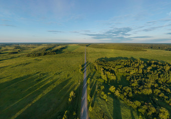 Road among forests and fields located on the border of the Ural and Siberia. Aerial, summer, sunny