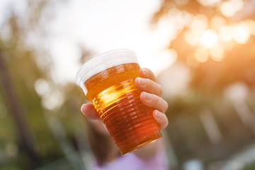 Woman holding cold glass of beer outdoors.