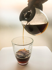 Drip coffee into a clear coffee cup. Focus can be selected at the drip of coffee.