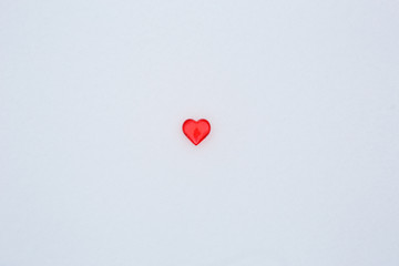 Red glass hearts on the snow. The symbols of love for Valentine's Day background with snow texture...