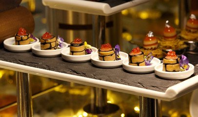 Salmon Gravlax covered wish Peanut garnished with caviar and flower ..Salmon fillet in jelly..Вeautiful serving in white porcelain plates on a black stone stand