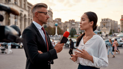 Professional reporter interviewing woman on urban street. Journalism industry, live streaming...