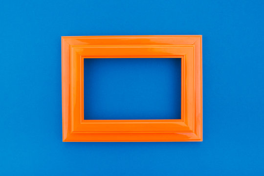 Empty orange frame on the classic blue background. Trendy greeting card. Minimal concept. Copy space for your text. Flat lay style. Top view. 