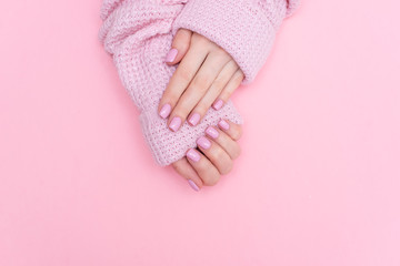 Female hands manicure close up view on pink knitted sweater background. Nail painting effects. Manicure salon banner concept