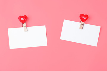 White sheets of note with hearts clothespins with text love, on a pink background. The concept of Valentine's Day, declaration of love. Copy space